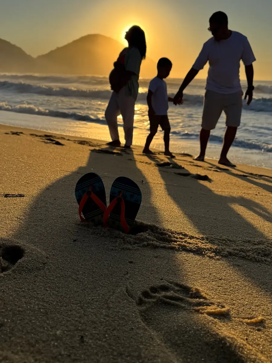 Família em silhueta na areia ao entardecer